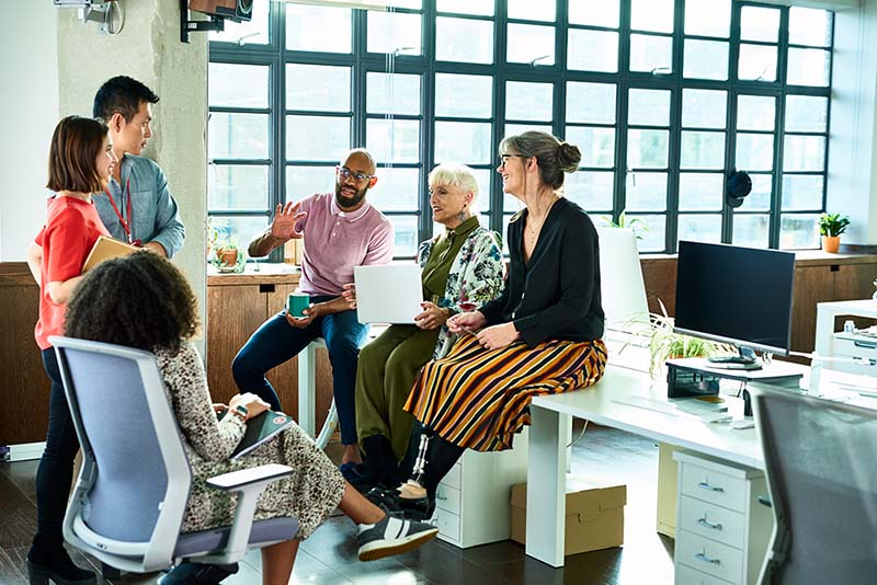 diverse group of young office workers meeting around a desk.